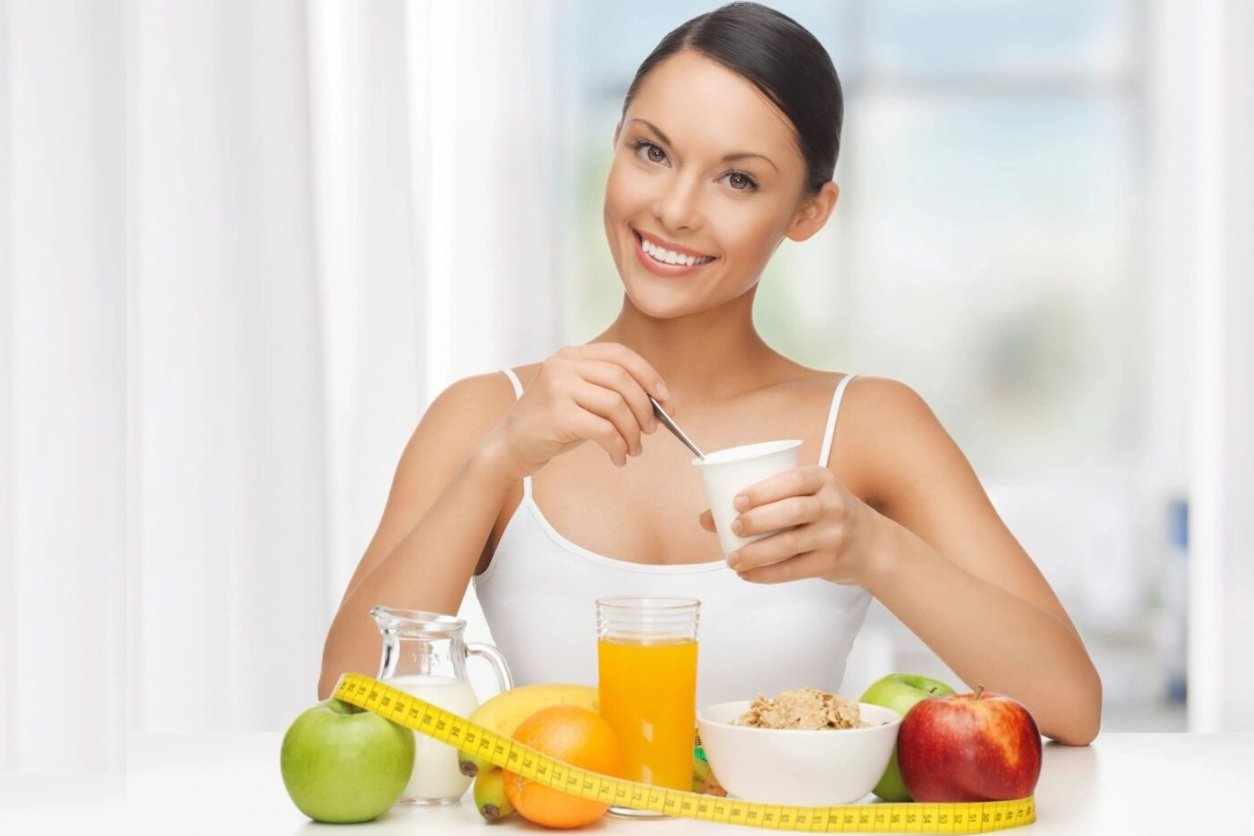 A woman sitting at the table with some fruit and juice.