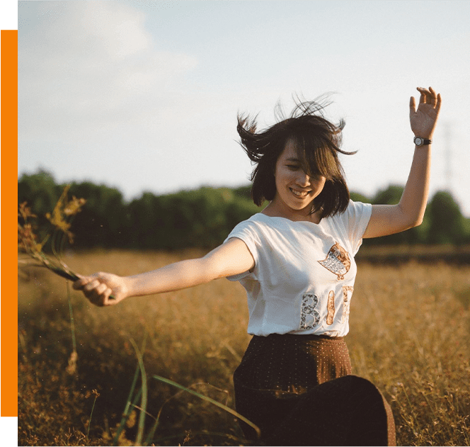 A woman in the middle of a field holding something.