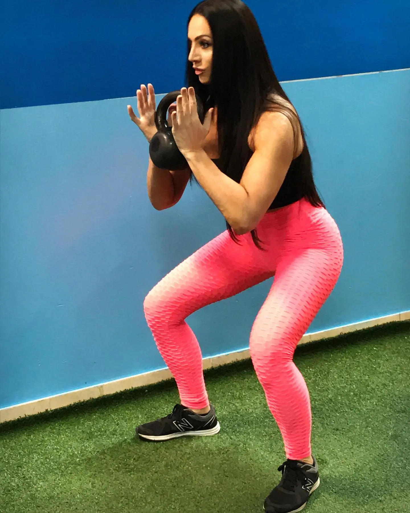 A woman in pink pants squats on the ground.