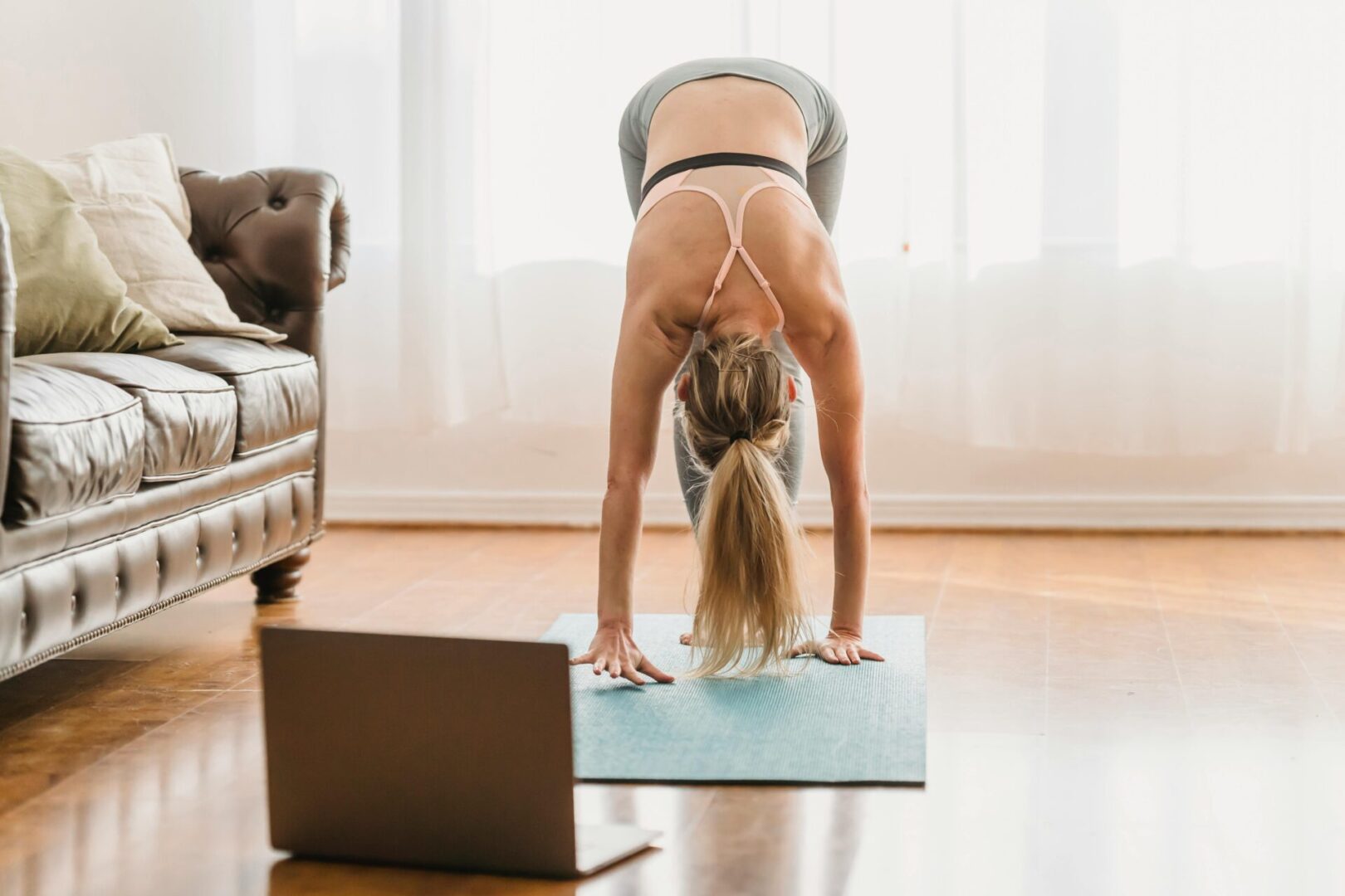 A woman is doing yoga in front of the laptop.